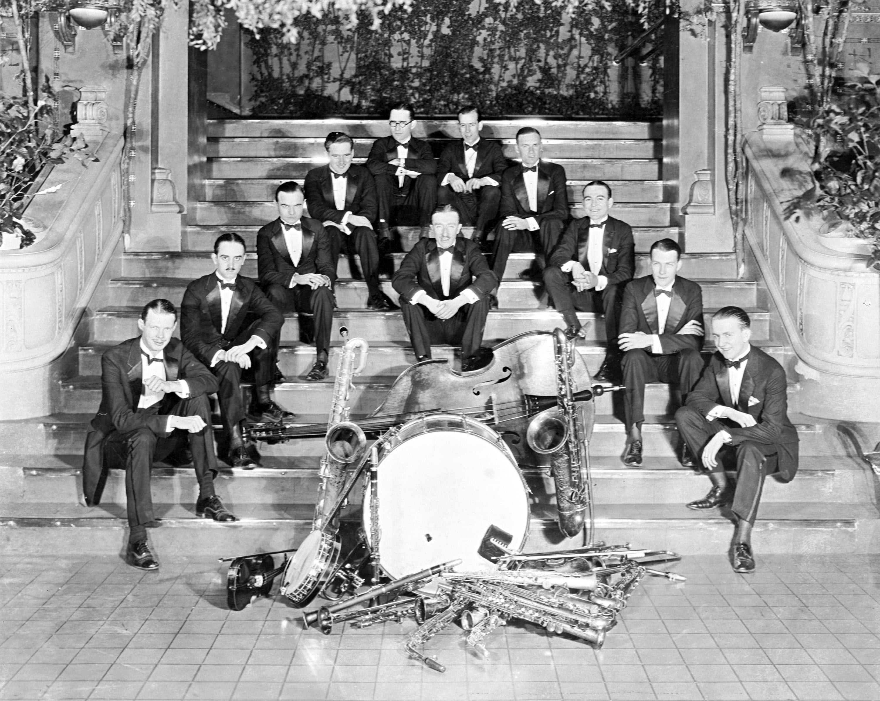 Herman Kenin band poses on staircase with instruments in the center.